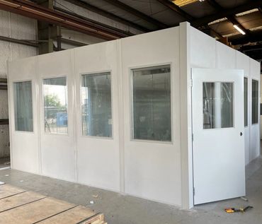 A pre-fabricated office with several windows in the front, door on the side. Inside a warehouse sett