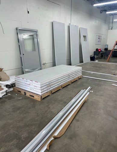 Materials for modular office solutions , including panels and a door, on a warehouse floor.