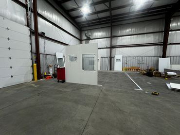 A prefab office under construction inside a warehouse setting, featuring a window