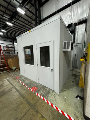 A small prefab office with a window, door, installed inside a warehouse setting. By SoFlo Installati