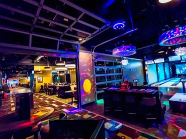Vibrant bowling alley with colorful lights and seating area.