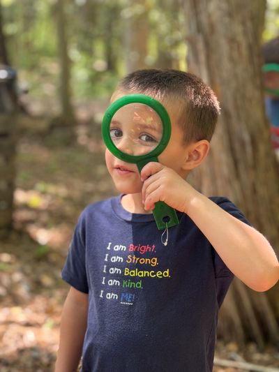 Boy holding a magnifying glass up to his eye.