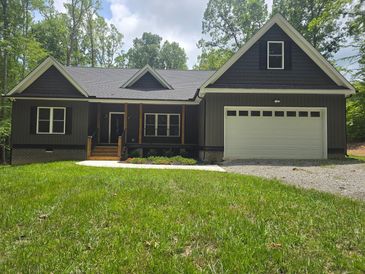 Modern black house with large garage and lush green lawn.