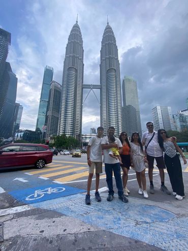 A group of six people posing in front of the Petronas Towers in Kuala Lumpur.