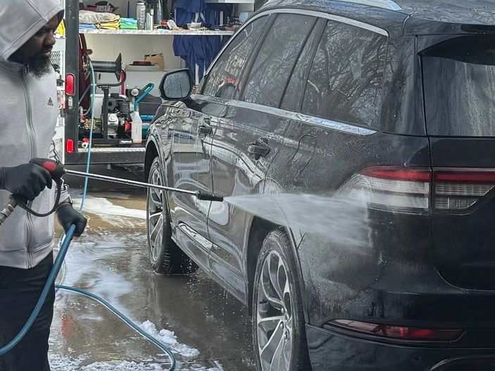 Close-up of me pressure washing the vehicle to loosen the dirt and prep for decontamination.