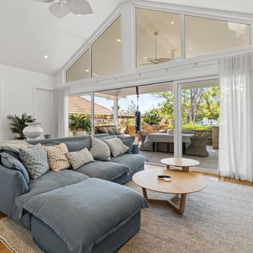 A lounge room with heigh ceilings and vgroove. Large windows with natural light