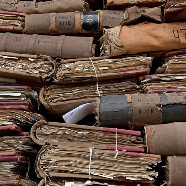 Stacks of old, worn deed books tied with string.
