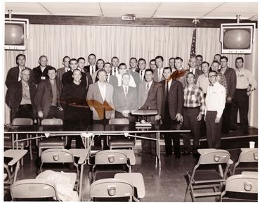 Gus Grissom being awarded a desk lamp by Mr. Bertram. Alan Shepard is second to Gus's right.
