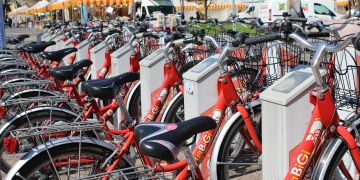 A row of red rental bicycles parked at a docking station.