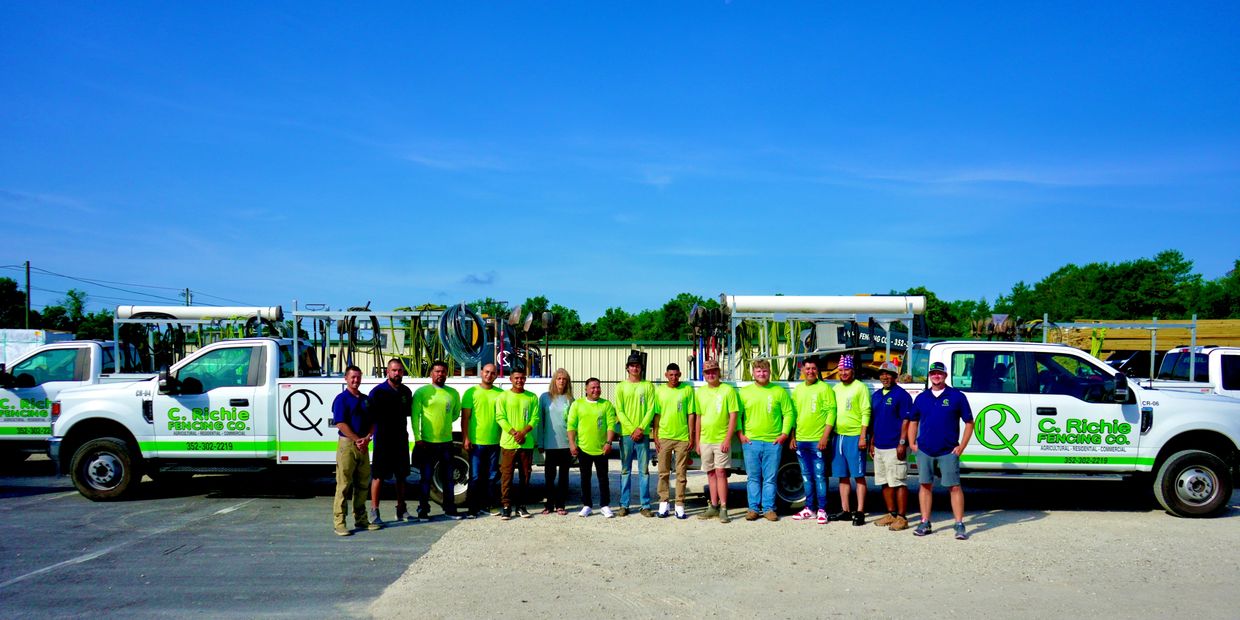 Team of fencing company employees standing between two company trucks.