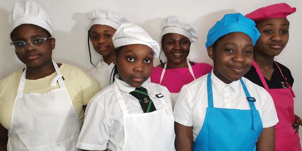 A group of children wearing chef hats and aprons at a cooking class