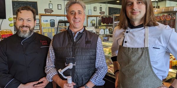 Two cooks with a man holding a phone stand