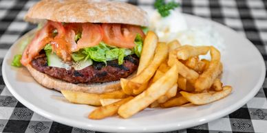 A sandwich with meat and vegetables next to fries