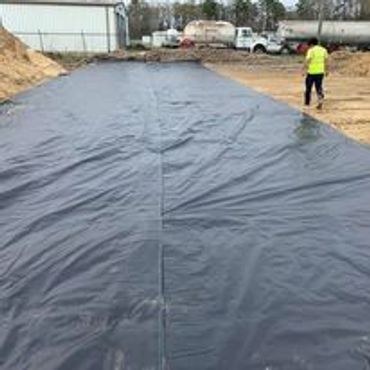 Large black tarp covering ground at a construction site.
