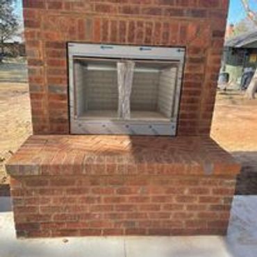 A brick outdoor fireplace with glass doors installed.