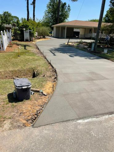 Freshly poured concrete driveway extending to a garage on a sunny day.