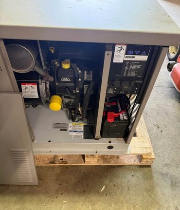 Open Kohler generator showing internal engine and battery components.