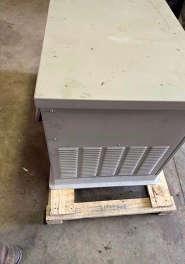 A large gray equipment box on a wooden pallet in a workshop.
