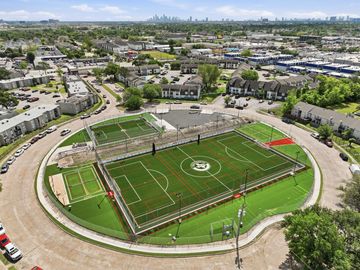 Aerial view of a fenced soccer field surrounded by urban buildings and streets.