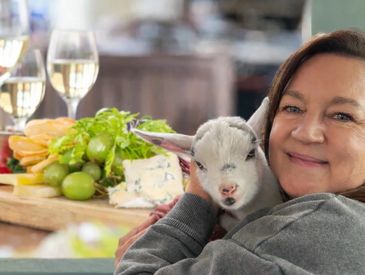 Woman holding a baby goat smiling.