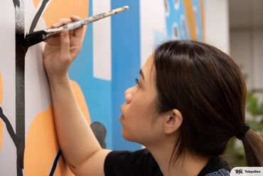 Artist and illustrator Fern Choonet painting a mural. Asian female artist drawing. 