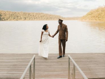 Bride and groom walk hand in hand on a dock after an intimate lakeside wedding surrounded by nature.