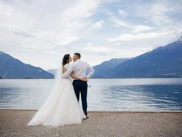 Couple embraces beside the water after a scenic destination wedding on a peaceful mountain lake