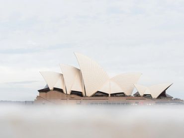 Iconic Sydney Opera House rises above soft mist and harbor waves on a peaceful Australian morning