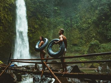 Couple at lush Hawaiian waterfall hike with inner tubes, perfect for nature lovers and adventure