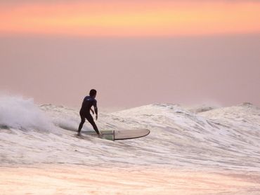 Man surfing ocean wave at Hawaii beach during golden sunset, perfect for adventure vacations