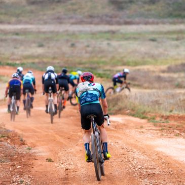 Group of cyclists racing on a dirt path.