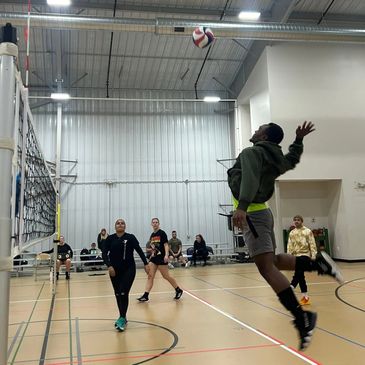 Young man jumping to spike a volleyball indoors.