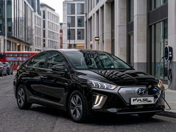 Black electric Hyundai car charging in an urban setting.