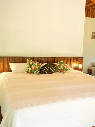 Cozy bedroom with wooden headboard and floral cushions.