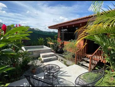 Cozy outdoor seating area with lush greenery and a small pool beside a wooden house.