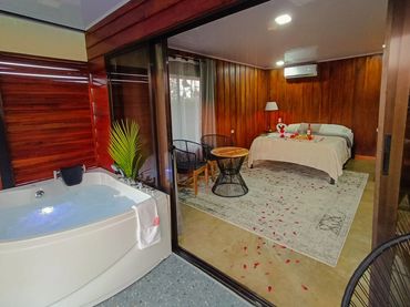 Cozy wooden room with a romantic bed setup and a jacuzzi tub.