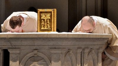 Two monks bowing in worship at an altar.