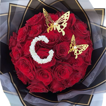 Elegant bouquet of red roses with golden butterflies and a white floral letter G.