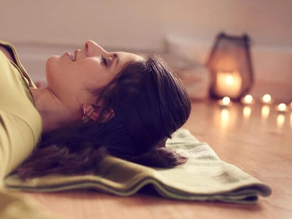 woman relaxing on yoga mat in restorative yoga