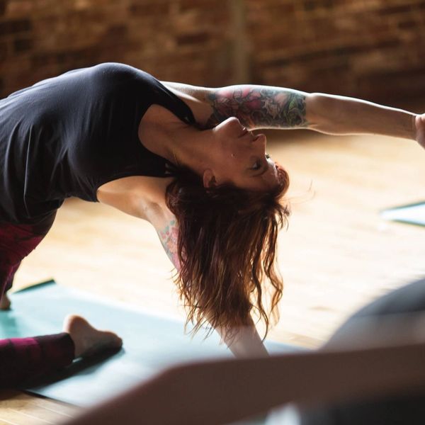attractive tattooed woman in backbend yoga posture reaching in yoga class in yoga studio