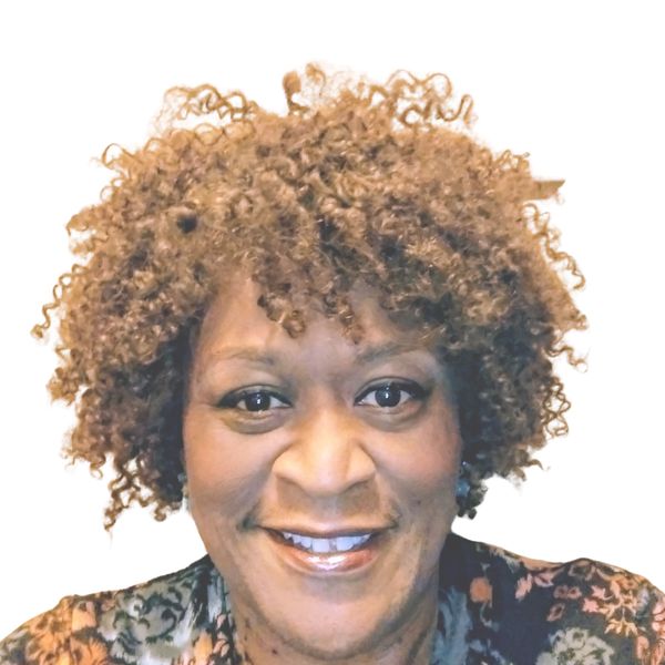 Smiling woman with curly hair and floral top.