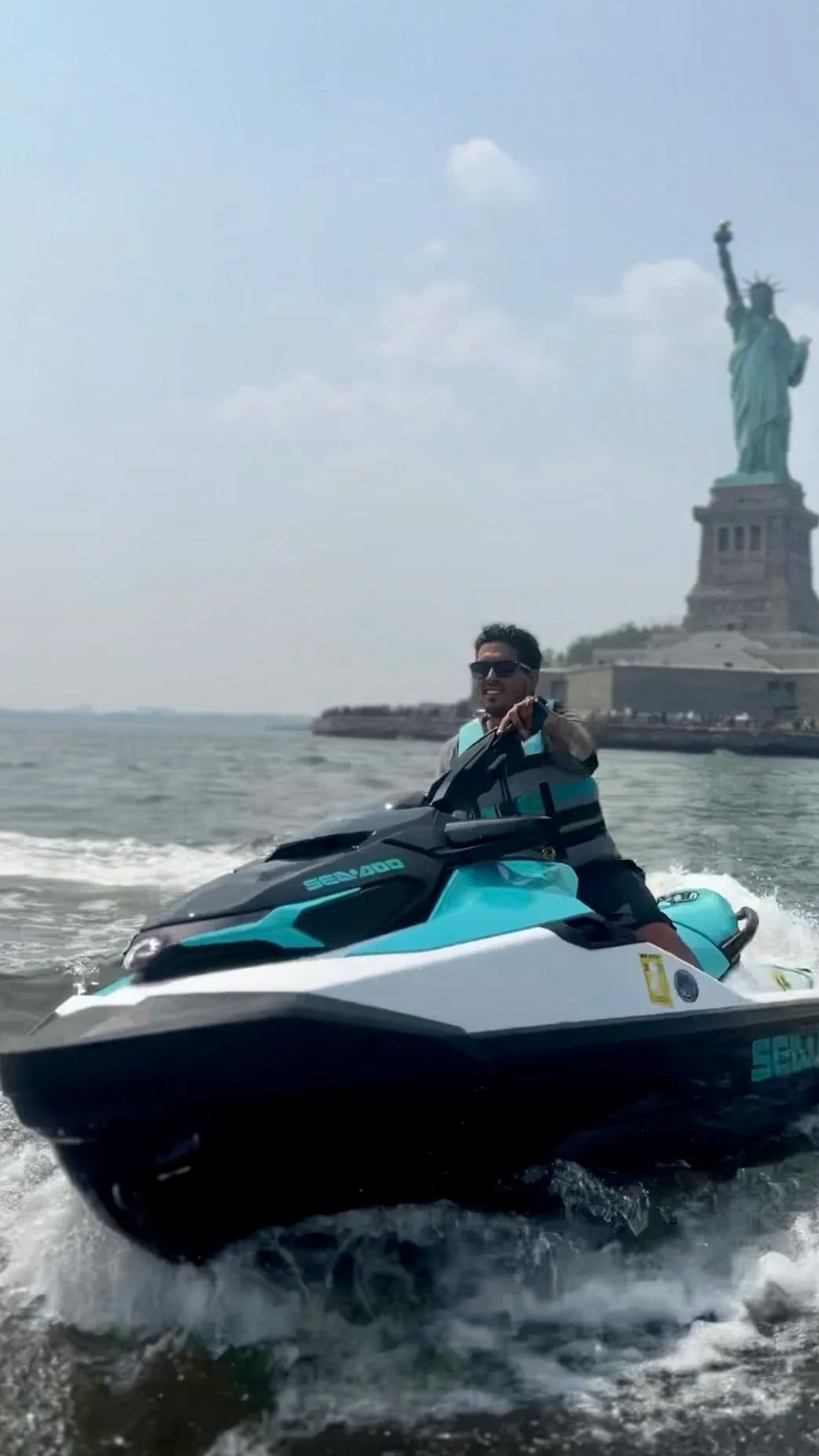 Guy jet ski in New York City harbor near Statue of Liberty having fun with friends and family