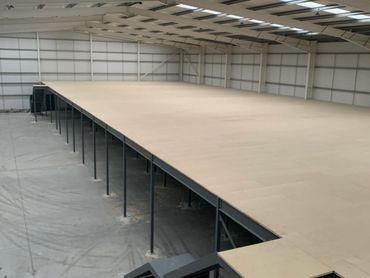 Large empty warehouse mezzanine platform with metal supports.