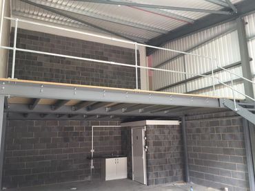 Interior of an industrial space with metal mezzanine and brick walls.