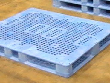 Gray plastic pallet on a wooden floor.