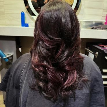 Shiny layered hairstyle with soft curls and subtle highlights.