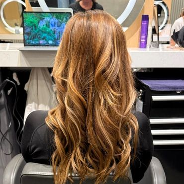 Long, wavy caramel-colored hair styled neatly in a salon.