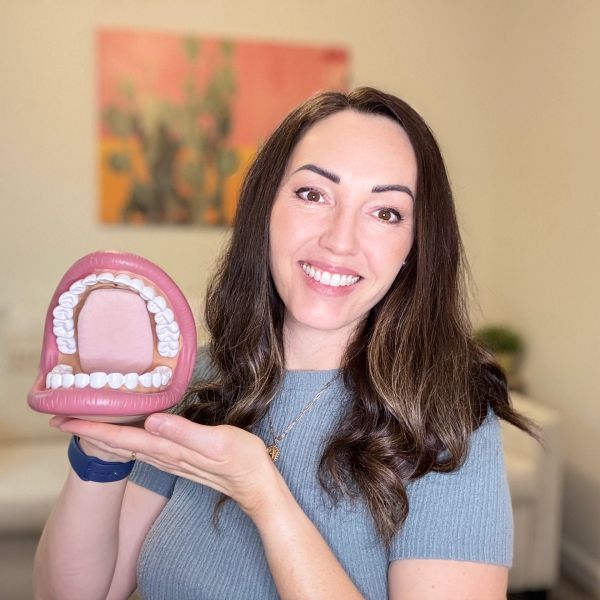 Woman smiling and holding a giant dental model.