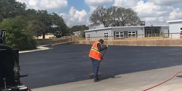 <img src="thumbnail_IMG_3895.jpg" alt="pavement worker brushing debris from parking lot"