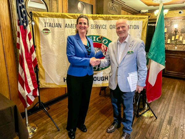 Two people shaking hands at an Italian American Service Organization event.